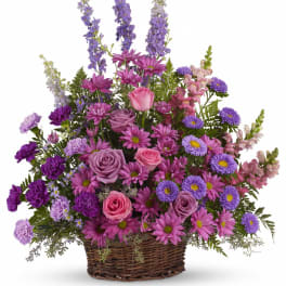 Pink and purple mixed flower arrangement in a wicker basket