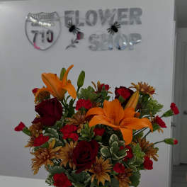 Orange lilies and red roses in a pumpkin-shaped container