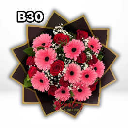Pink gerbera daisies and red roses in a dark wrapped bouquet