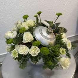 White roses and green button mums arranged around a silver ornament