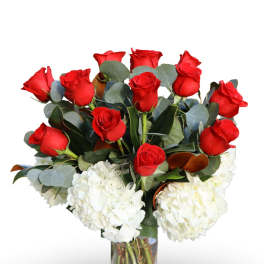 Red roses and white hydrangeas in a clear glass vase