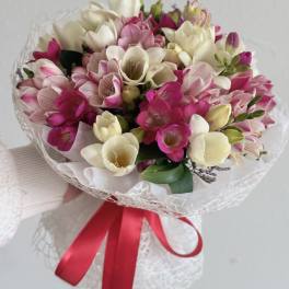 Bouquet of pink and white freesia wrapped with a red ribbon
