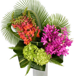 Tropical bouquet of pink and orange flowers in a tall white vase