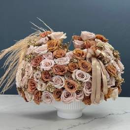 Large bouquet of pale roses in a white vase with a ribbon
