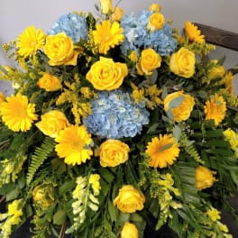 Yellow roses and daisies with blue hydrangeas in a large spray arrangement