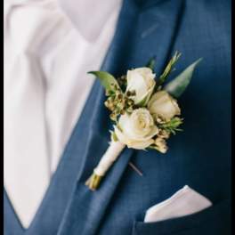 White rose boutonniere pinned to a blue suit jacket