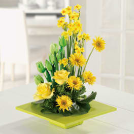 Yellow flowers and roses arranged on a lime-green square base