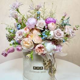 Pastel bouquet of roses and peonies in a round hatbox
