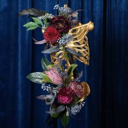 Floral arrangement on a gold ribcage sculpture against a blue curtain