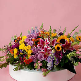Colorful mixed flower arrangement in a white round box