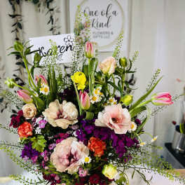 Mixed bouquet of tulips, roses, and small daisies in a gold vase