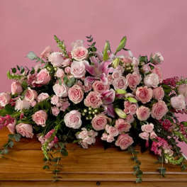 Pink rose and lily casket spray on a wooden casket