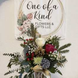 Holiday bouquet in a glass vase with roses, pinecones, and evergreen sprigs
