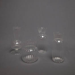 Set of four clear ribbed glass bud vases on a gray background