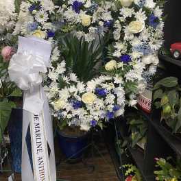Large white floral wreath with cream roses and blue accents on an easel