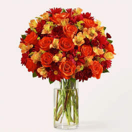 Orange and red flower bouquet in a clear glass vase