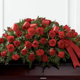 Red roses and carnations arranged with red ribbon on a casket