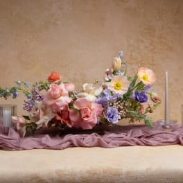 Low floral centerpiece with pink, white, and lavender blooms on a table