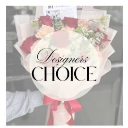 Bouquet of red and blush roses wrapped in pale paper with a pink ribbon