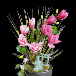 Pink magnolia-like flowers in a black pot with a small Buddha figurine