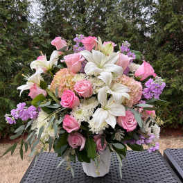 Pink roses and white lilies arranged in a white vase