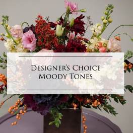 Mixed floral arrangement in a dark vase with pink, burgundy, and cream blooms