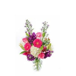 Bright mixed bouquet of pink gerbera daisies, roses, and white hydrangea in a clear glass vase