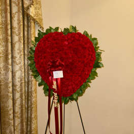 Heart-shaped red floral standing tribute on an easel with ribbon
