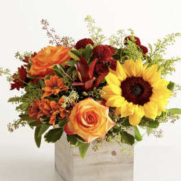 Mixed bouquet with sunflowers and orange roses in a wooden box