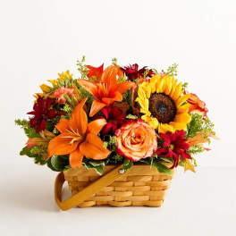 Basket arrangement with sunflowers, orange lilies, and red flowers