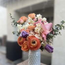 Bouquet of pink, orange, and white flowers in a textured glass vase