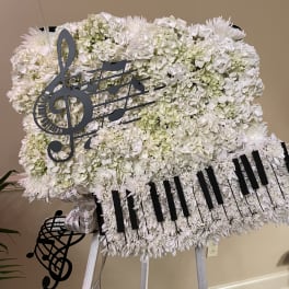 White floral standing spray with music note decorations on an easel