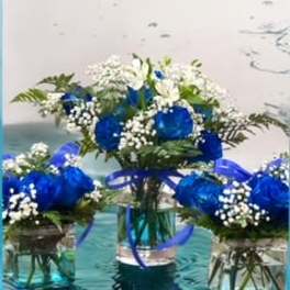 Blue and white flower arrangements in glass vases with ribbon