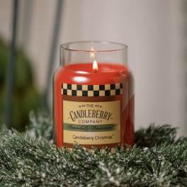 Lit red candle in a glass jar surrounded by snowy evergreen branches