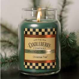 Green candle in a glass jar with a lit wick and labeled front
