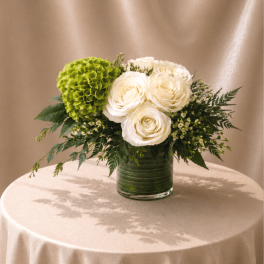 White roses and a green hydrangea in a glass vase