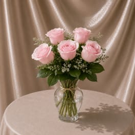 Pink roses arranged in a clear glass vase with small white filler flowers