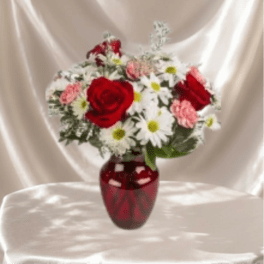 Red roses and white daisies arranged in a red vase