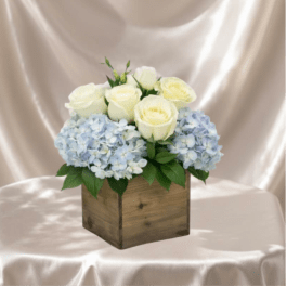 White roses and pale blue hydrangeas in a wooden box
