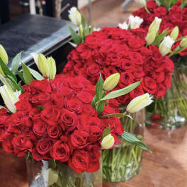Bouquets of red roses with white lily buds in glass vases