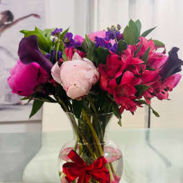 Pink and purple bouquet in a clear vase with a red ribbon