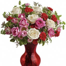 Bouquet of pink, white, and red roses in a red glass vase