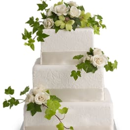 Three-tier white wedding cake with white roses and ivy