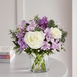 White rose and purple flower bouquet in a clear glass vase