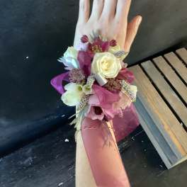 Wrist corsage with cream and magenta flowers on a ribbon band