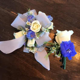 Small corsage and boutonniere with white and blue flowers and lavender ribbon