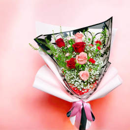 Bouquet of red and pink roses wrapped in white paper with a pink ribbon