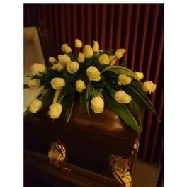 White rose arrangement on a dark casket