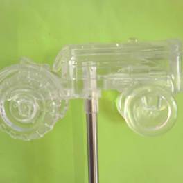Clear plastic toy car mounted on a metal rod against a green background