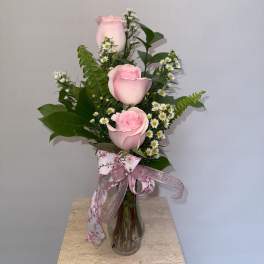 Pink roses arranged in a clear glass vase with small white daisies